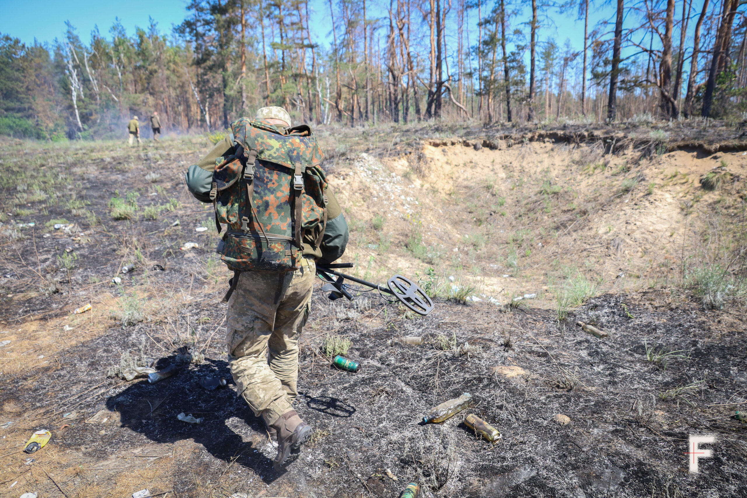 Військовий шукає міни на території лісництва